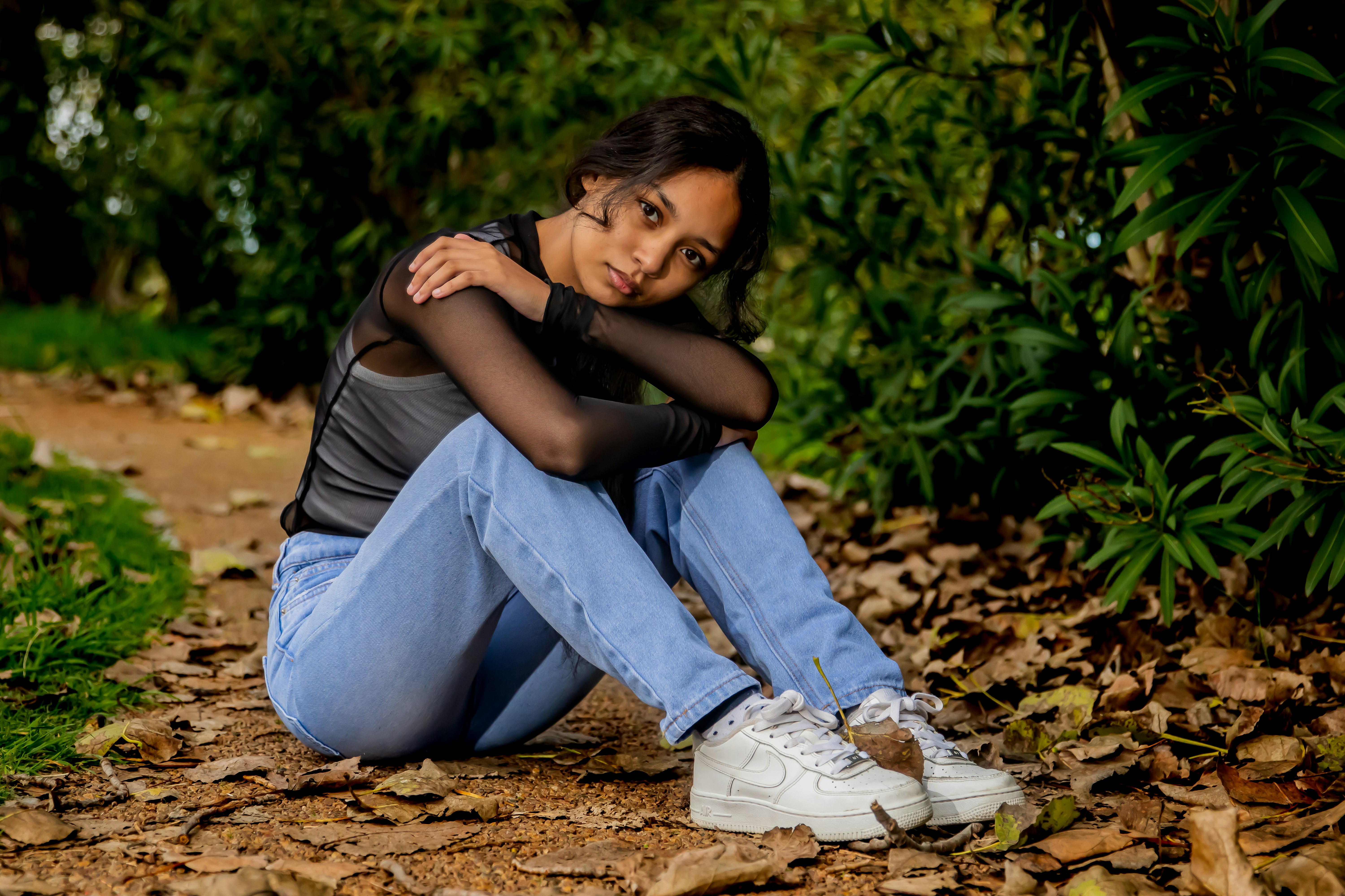 man in black t-shirt and blue denim jeans sitting on ground